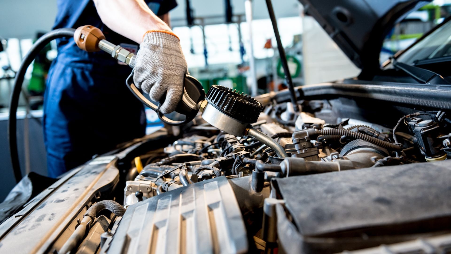 Mechanic working on car engine with tools in automotive repair shop