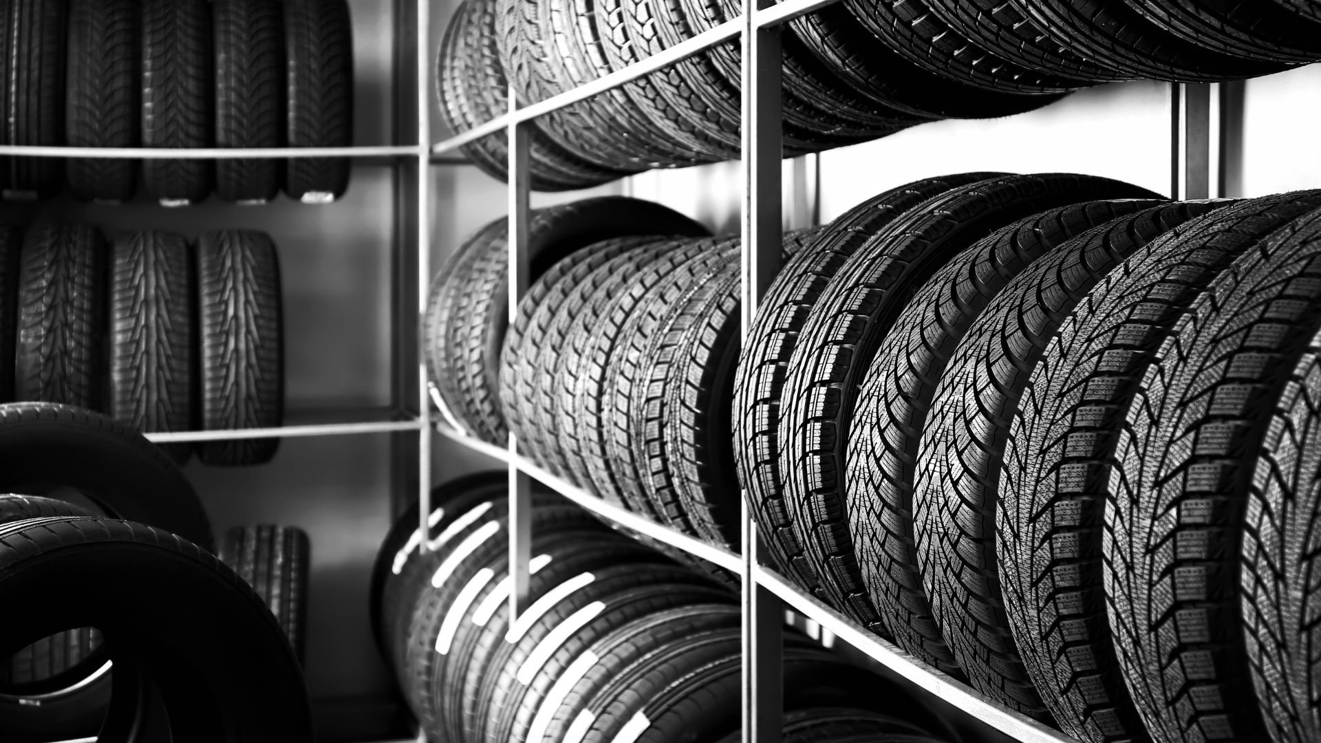 Stacked car tires on metal shelves in a black and white image